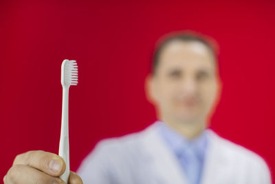 Close-up portrait of man holding red over white background