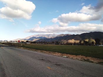 Empty road along landscape and mountains against sky