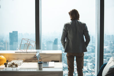 Rear view of man standing by window