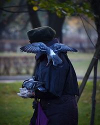 Pigeons perching on person standing at field