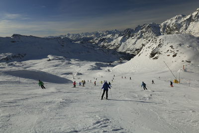 People skiing on snowcapped mountain against sky