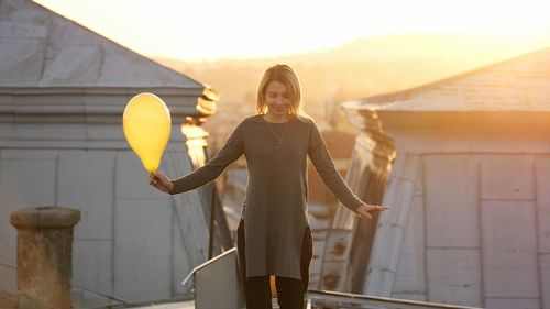 Woman standing on roof during sunset