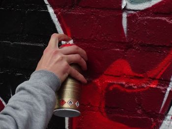 Cropped image of person making graffiti on wall