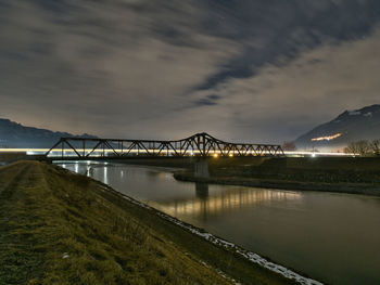 Bridge over river against sky at night