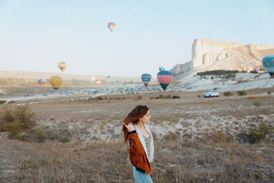 Young woman with balloons on landscape against sky