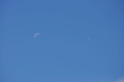 Low angle view of moon in blue sky