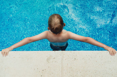 Rear view of girl swimming in pool