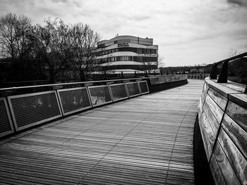 View of footbridge in city against cloudy sky