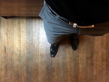 Low section of man sitting on hardwood floor