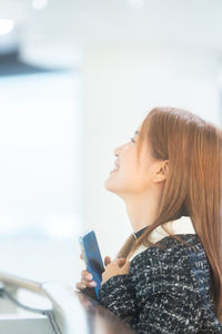 Side view of young woman using mobile phone