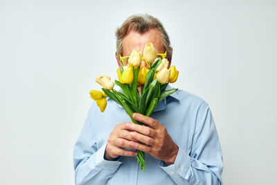 Portrait of smiling woman holding potted plant against white background