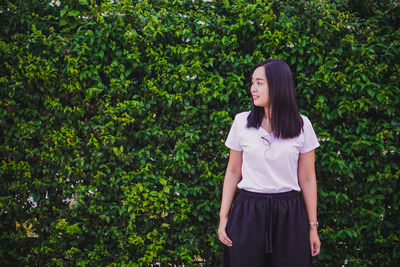 Young woman standing against plants