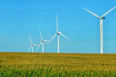 Wind turbines on field against clear sky