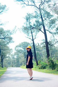Portrait of young woman standing against trees