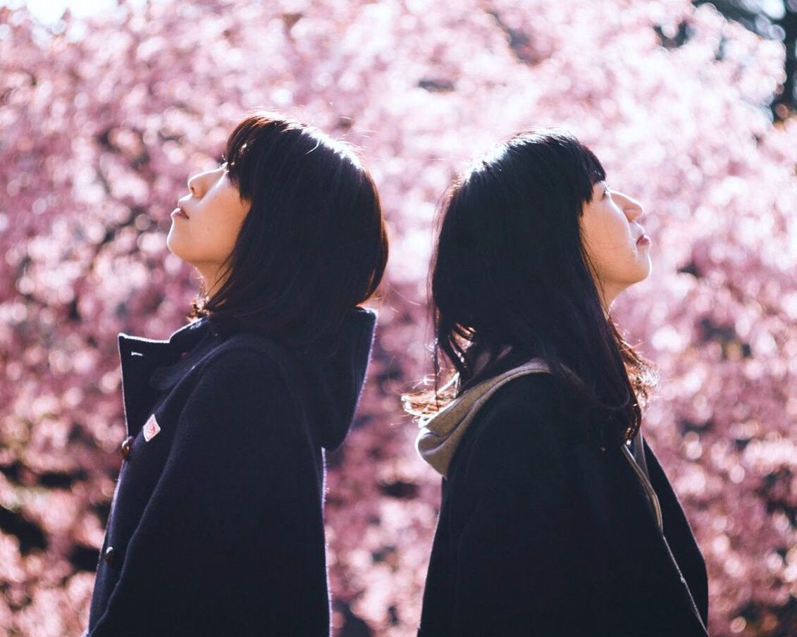 women, two people, real people, adult, side view, lifestyles, bonding, plant, focus on foreground, young women, nature, togetherness, leisure activity, people, standing, tree, flowering plant, flower, day, young adult, outdoors, positive emotion, hairstyle, couple - relationship, cherry blossom