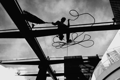 Low angle view of silhouette man working against sky in city