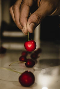 Close-up of hand holding strawberry on table