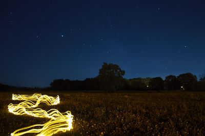 Scenic view of illuminated field against sky at night