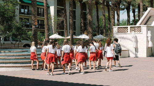 Rear view of people walking on street in city