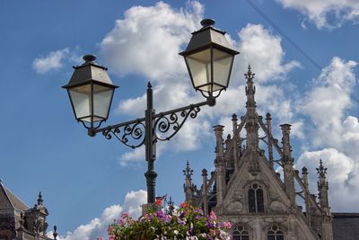 Low angle view of street light by building against sky