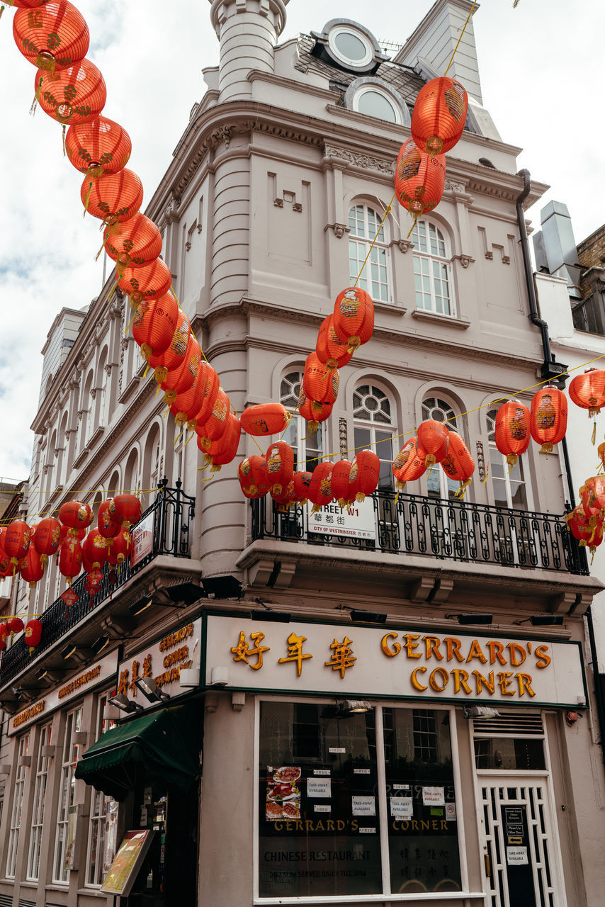 LOW ANGLE VIEW OF LANTERNS HANGING BY BUILDING IN CITY AGAINST SKY