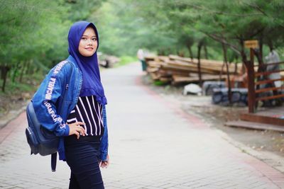 Portrait of woman standing on footpath