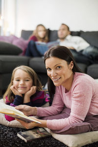 Portrait of happy mother and daughter with story book in living room