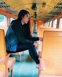 Side view of young woman sitting on chair