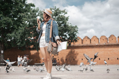 Full length of woman standing by birds outdoors