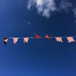 Low angle view of flags hanging against blue sky