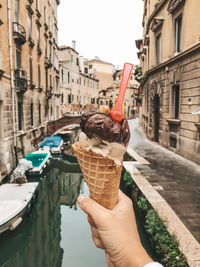 Cropped image of woman holding ice cream cone in canal