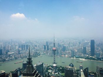 Oriental pearl tower by huangpu river against sky in city