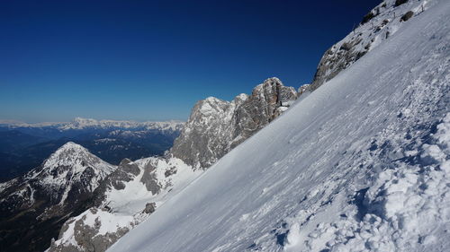 Scenic view of snowcapped mountains against clear blue sky