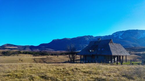 Scenic view of field and mountains against clear blue sky