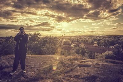 Man standing on road against sky during sunset