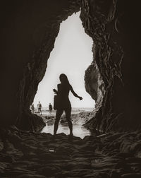 Silhouette woman by rock formation at beach