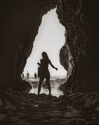 Silhouette people standing on rock by sea against sky