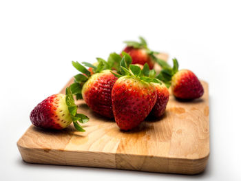 Close-up of strawberries on cutting board against white background