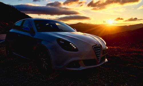 View of car on landscape against sunset sky