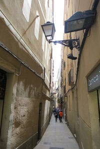 Rear view of people walking on footpath amidst buildings in city