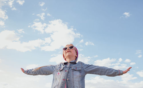 Little girl raised arms blue sky. happy child smiling flying in the air. lifestyle freedom happiness