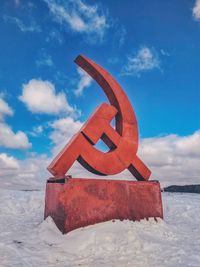 Traditional windmill on snow field against sky