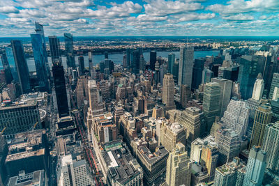 Aerial view of illuminated skyscraper buildings in city at day at high angle