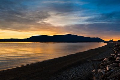 Scenic view of beach at orcas island against cloudy sky during sunset