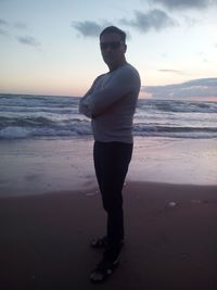 Portrait of man standing on beach against sky during sunset