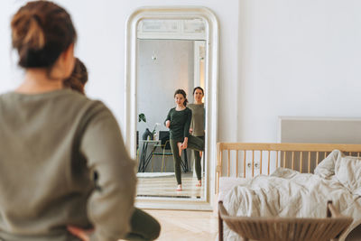 Rear view of couple standing on bed at home