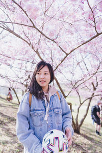 A lady standing under pink cherry blossom 