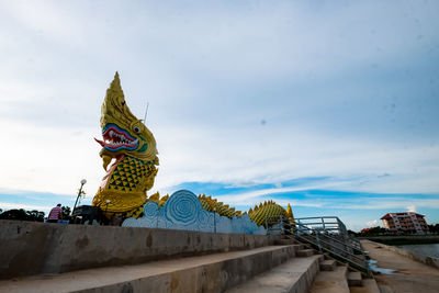 Panoramic view of sculpture by building against sky