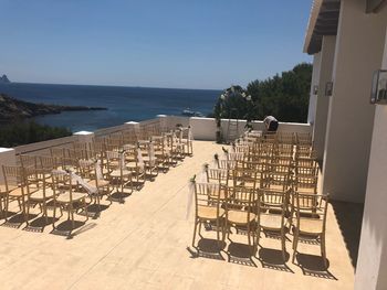 Chairs on table by sea against clear sky