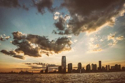 Sea and cityscape against sky during sunset